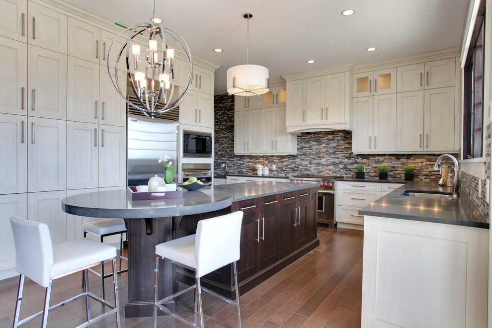 Cette image montre une cuisine américaine design avec un placard à porte shaker, des portes de placard blanches, une crédence multicolore et un électroménager en acier inoxydable.