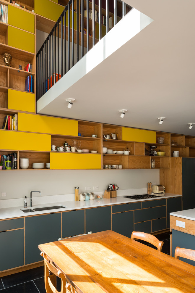ロンドンにあるコンテンポラリースタイルのおしゃれなキッチン (中間色木目調キャビネット、クオーツストーンカウンター、白いキッチンパネル、石スラブのキッチンパネル、パネルと同色の調理設備、スレートの床) の写真