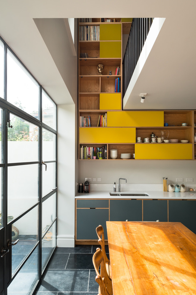 Moderne Wohnküche mit hellbraunen Holzschränken, Küchenrückwand in Weiß, Schieferboden, Doppelwaschbecken und offenen Schränken in London