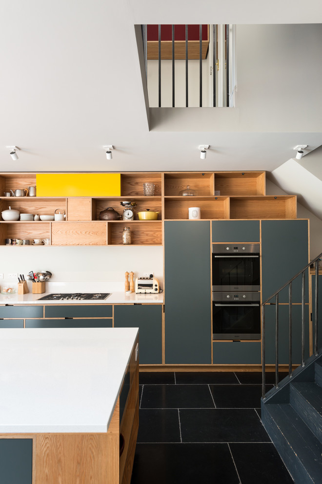 Trendy slate floor eat-in kitchen photo in London with medium tone wood cabinets, quartz countertops, white backsplash, stone slab backsplash, paneled appliances and an island