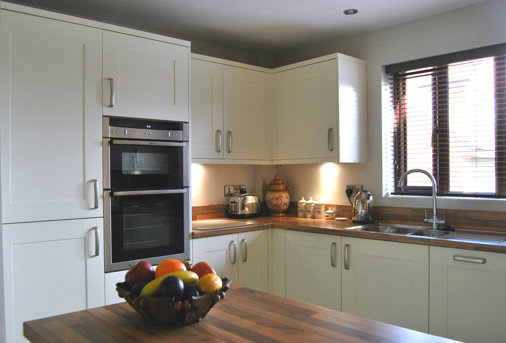 Esempio di una piccola cucina abitabile chic con ante in stile shaker, ante bianche, top in laminato, paraspruzzi marrone e penisola