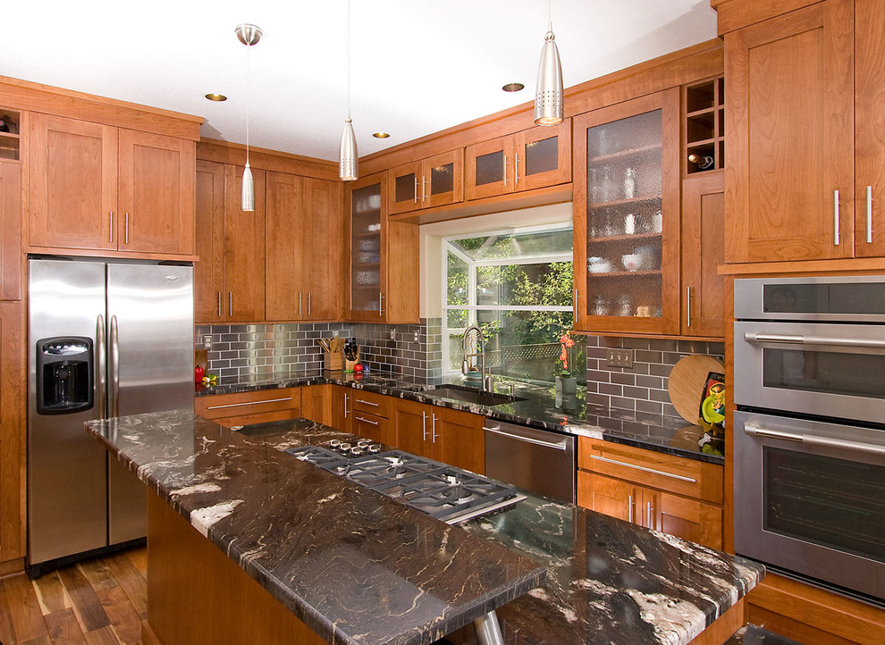 Foto på ett vintage kök, med rostfria vitvaror, en enkel diskho, skåp i shakerstil, skåp i mellenmörkt trä, granitbänkskiva, stänkskydd med metallisk yta och stänkskydd i metallkakel