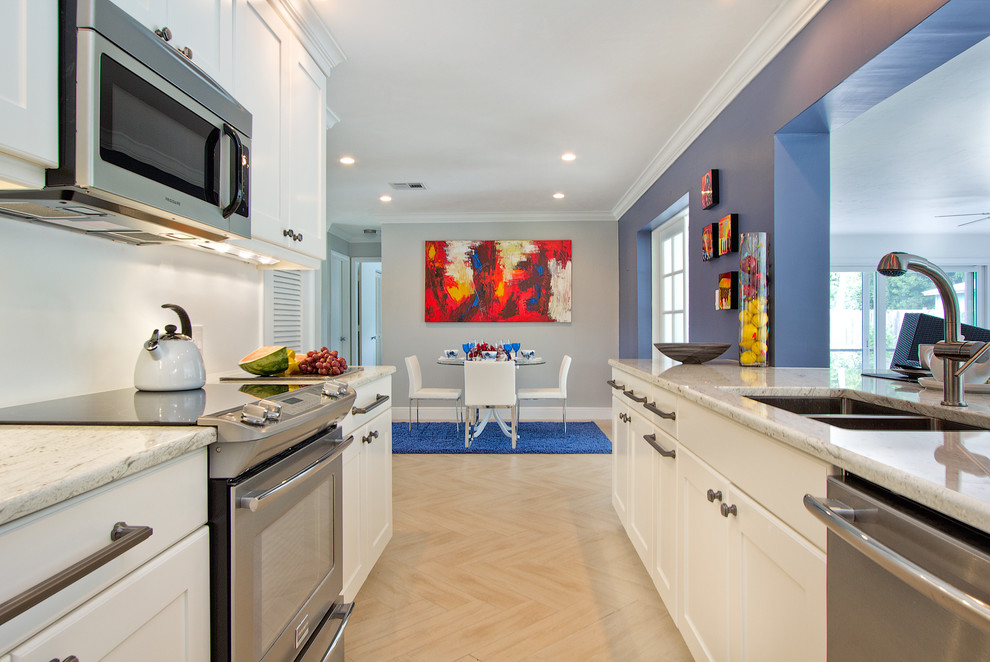 マイアミにある高級な中くらいなコンテンポラリースタイルのおしゃれなキッチン (ダブルシンク、落し込みパネル扉のキャビネット、シルバーの調理設備、白いキャビネット、アイランドなし) の写真