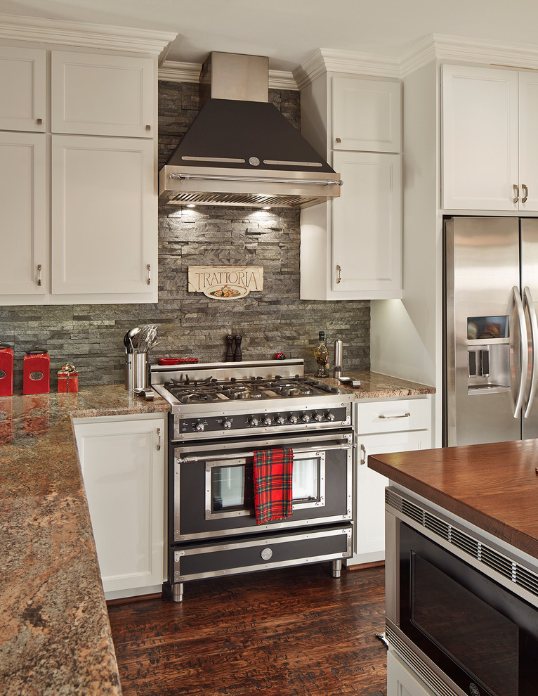 Example of a mid-sized classic u-shaped dark wood floor and brown floor kitchen design in Dallas with recessed-panel cabinets, white cabinets, gray backsplash, black appliances, slate backsplash, granite countertops and an island