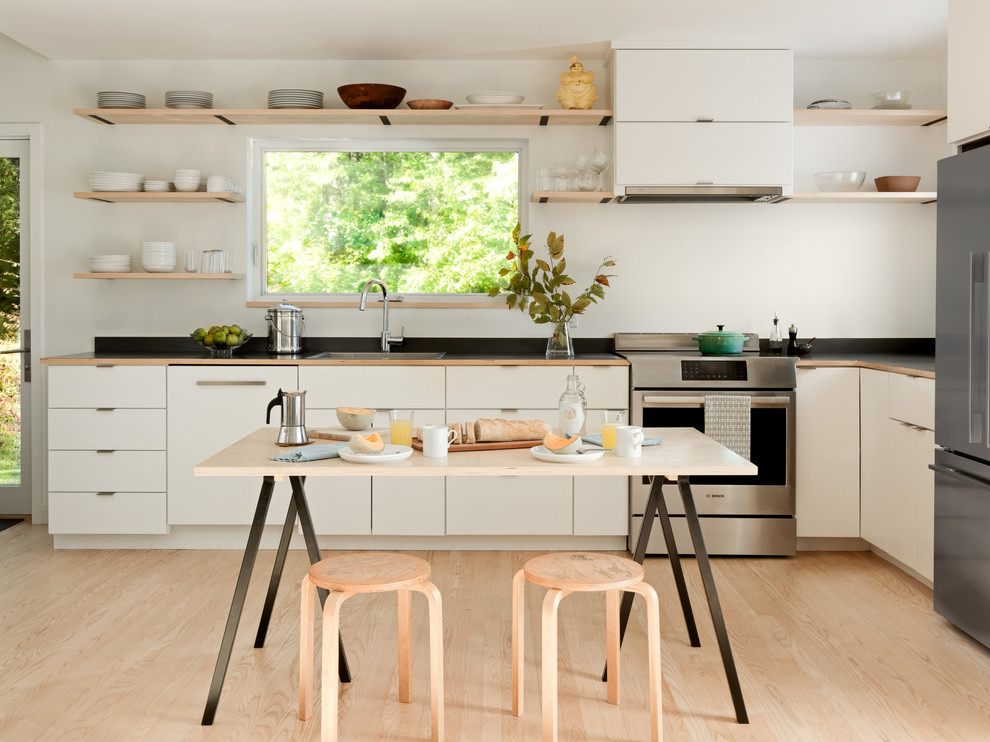 Esempio di una cucina scandinava con ante lisce, ante bianche, elettrodomestici in acciaio inossidabile, parquet chiaro e pavimento beige