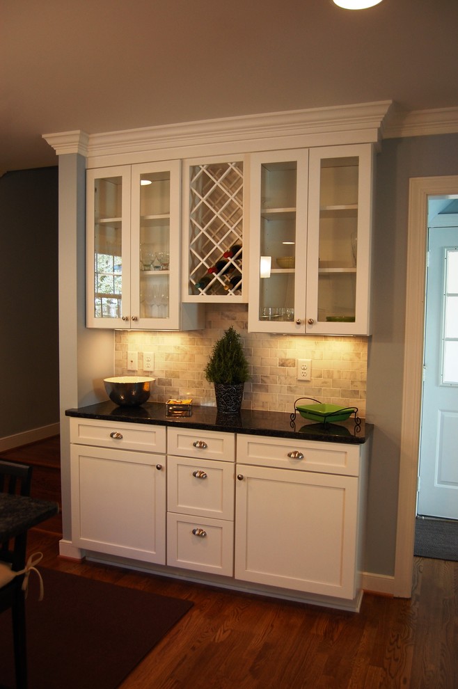 Exemple d'une arrière-cuisine chic avec des portes de placard blanches, un placard à porte vitrée, un plan de travail en quartz, une crédence beige, une crédence en carrelage de pierre, parquet foncé et un sol marron.
