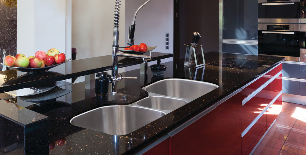 Exempel på ett stort modernt kök, med en undermonterad diskho, släta luckor, röda skåp, bänkskiva i återvunnet glas, svart stänkskydd, rostfria vitvaror, linoleumgolv och en köksö
