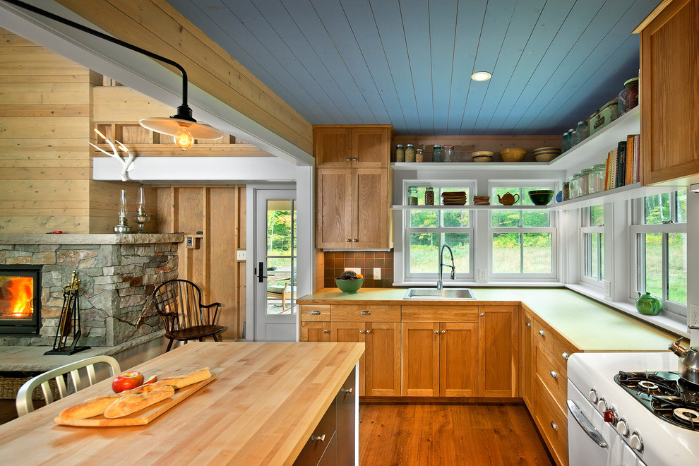 Open concept kitchen - mid-sized country l-shaped medium tone wood floor open concept kitchen idea in Minneapolis with a drop-in sink, shaker cabinets, medium tone wood cabinets, wood countertops, brown backsplash, white appliances and an island