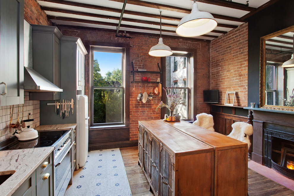 Example of a mid-sized eclectic single-wall ceramic tile kitchen design in New York with an undermount sink, shaker cabinets, gray cabinets, granite countertops, white backsplash, subway tile backsplash, stainless steel appliances and an island