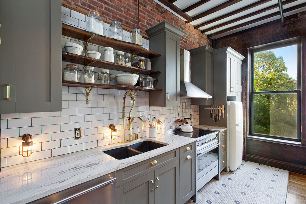 Medium sized retro single-wall kitchen/diner in New York with a submerged sink, recessed-panel cabinets, grey cabinets, granite worktops, white splashback, metro tiled splashback, stainless steel appliances and an island.