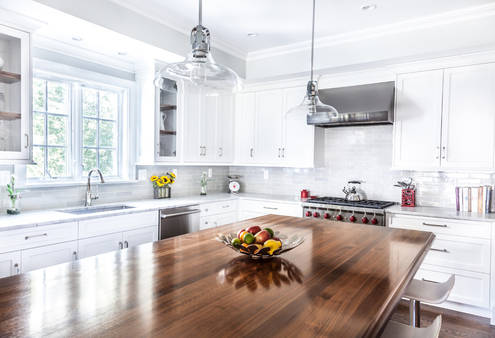 Mid-sized transitional l-shaped dark wood floor eat-in kitchen photo in New York with an undermount sink, beaded inset cabinets, white cabinets, wood countertops, white backsplash, subway tile backsplash, stainless steel appliances and an island