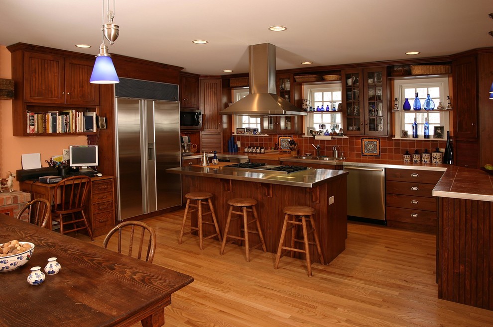 Foto på ett mellanstort vintage kök, med en dubbel diskho, luckor med infälld panel, skåp i mörkt trä, kaklad bänkskiva, stänkskydd i keramik, rostfria vitvaror, mellanmörkt trägolv, en köksö, brunt stänkskydd och brunt golv