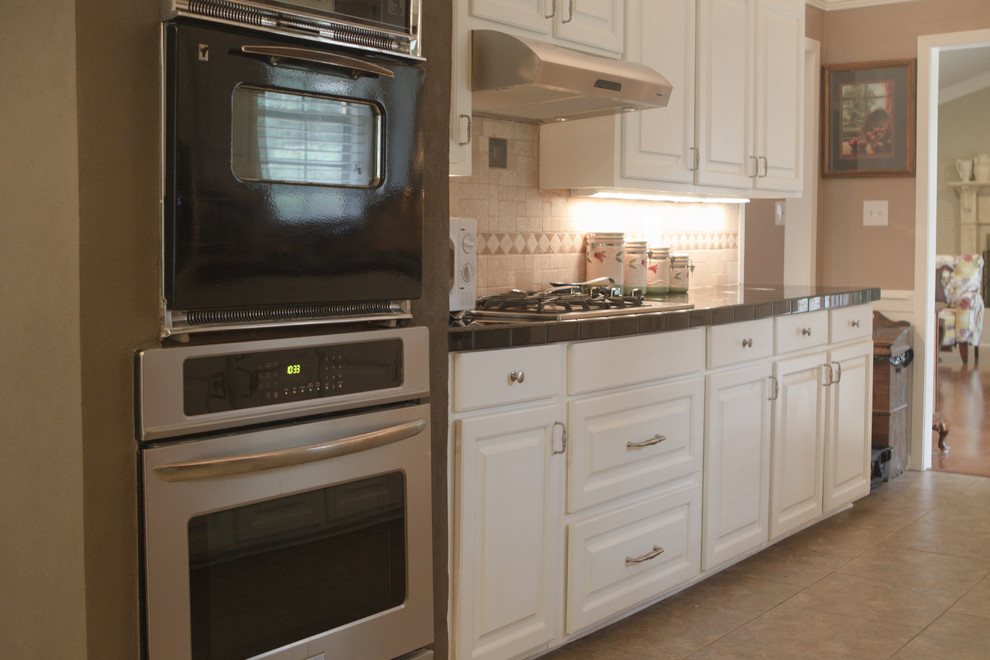 ジャクソンにある高級な中くらいなトラディショナルスタイルのおしゃれなキッチン (レイズドパネル扉のキャビネット、白いキャビネット、タイルカウンター、ベージュキッチンパネル、セラミックタイルのキッチンパネル、シルバーの調理設備、アイランドなし、ダブルシンク、セラミックタイルの床) の写真