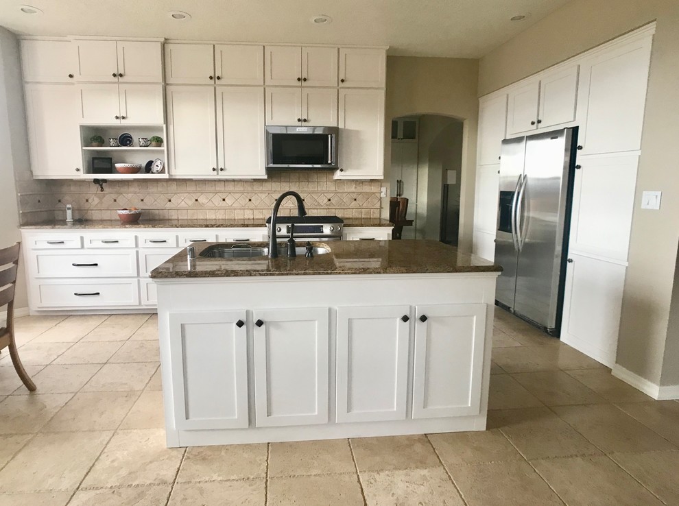 Example of a mid-sized transitional single-wall travertine floor and brown floor eat-in kitchen design in Albuquerque with an undermount sink, shaker cabinets, white cabinets, granite countertops, brown backsplash, travertine backsplash, stainless steel appliances, an island and brown countertops
