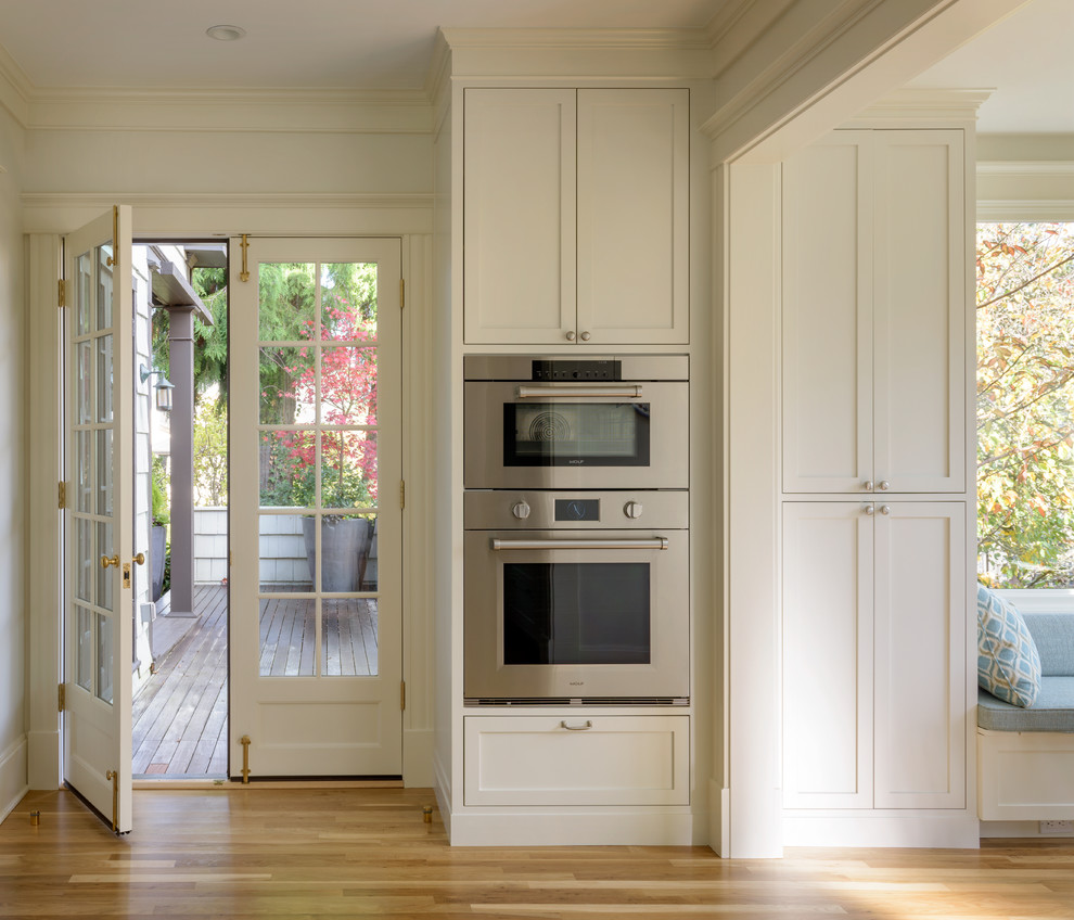 Diseño de cocina clásica renovada de tamaño medio con armarios estilo shaker, puertas de armario blancas, electrodomésticos de acero inoxidable y una isla