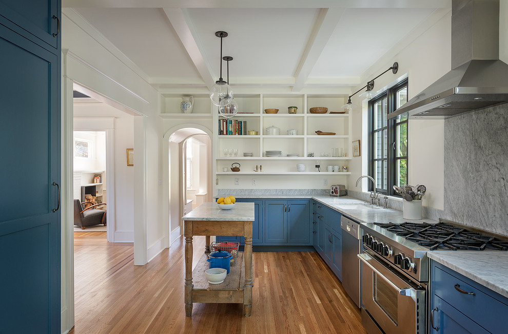 Exempel på ett avskilt, mellanstort lantligt l-kök, med luckor med infälld panel, blå skåp, vitt stänkskydd, stänkskydd i sten, rostfria vitvaror, mellanmörkt trägolv och en köksö