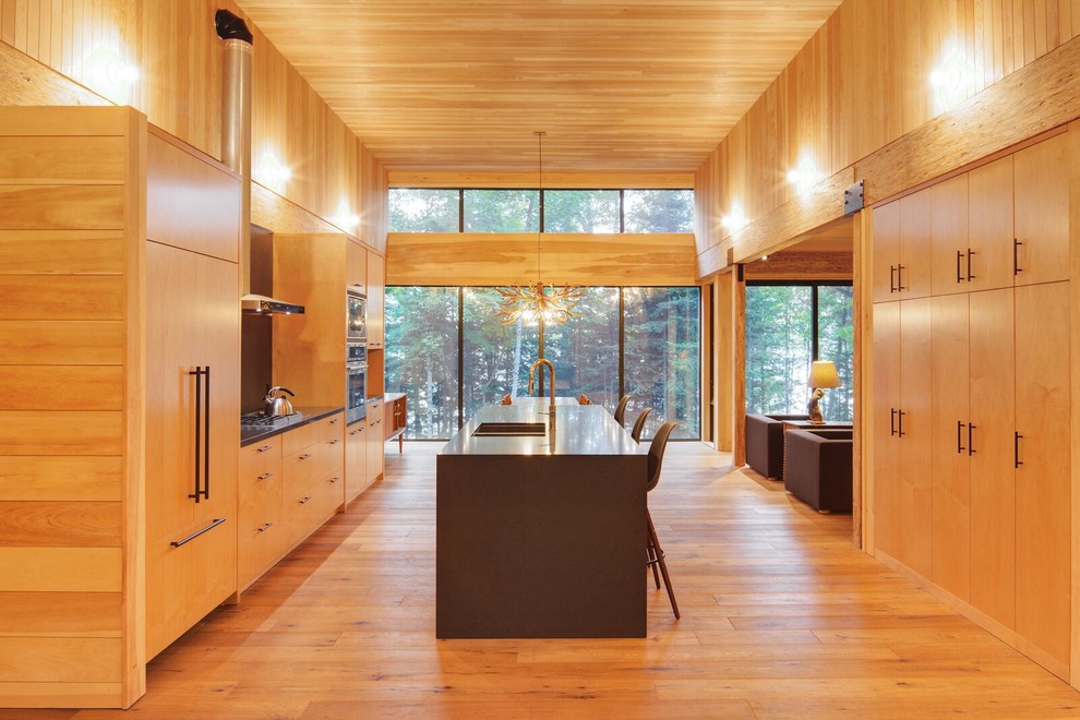Foto på ett stort funkis kök, med en nedsänkt diskho, släta luckor, skåp i ljust trä, rostfria vitvaror, ljust trägolv, en köksö och granitbänkskiva