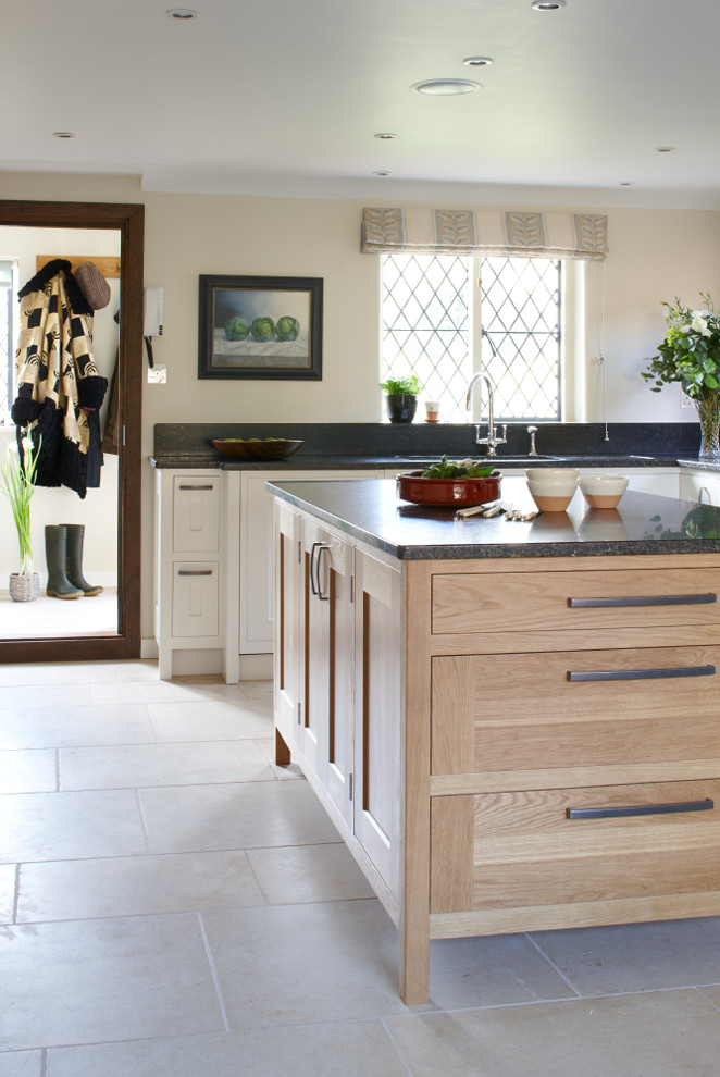Exempel på ett stort modernt kök, med en dubbel diskho, skåp i shakerstil, skåp i ljust trä, granitbänkskiva, svart stänkskydd, stänkskydd i sten, rostfria vitvaror, kalkstensgolv och en köksö
