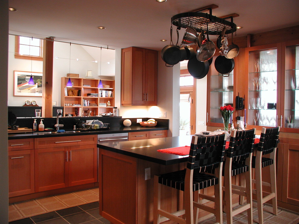 This is an example of a small classic kitchen in Seattle with a double-bowl sink, shaker cabinets, medium wood cabinets, composite countertops, ceramic flooring, a breakfast bar and black floors.