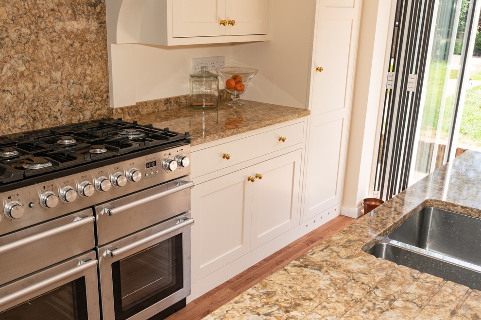 Exempel på ett mycket stort klassiskt brun brunt kök, med en dubbel diskho, skåp i shakerstil, beige skåp, bänkskiva i kvartsit, brunt stänkskydd, stänkskydd i sten, integrerade vitvaror, mellanmörkt trägolv, en köksö och brunt golv