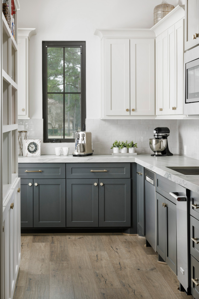 Modelo de cocina clásica renovada grande con puertas de armario grises, salpicadero blanco, electrodomésticos de acero inoxidable, suelo laminado, una isla, suelo gris y encimeras blancas