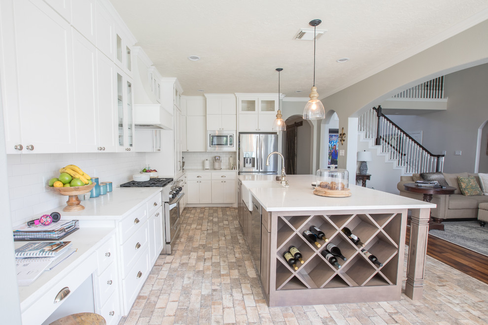 Design ideas for a traditional kitchen in Houston with a belfast sink, shaker cabinets, white cabinets, engineered stone countertops, white splashback, metro tiled splashback, stainless steel appliances, porcelain flooring and an island.