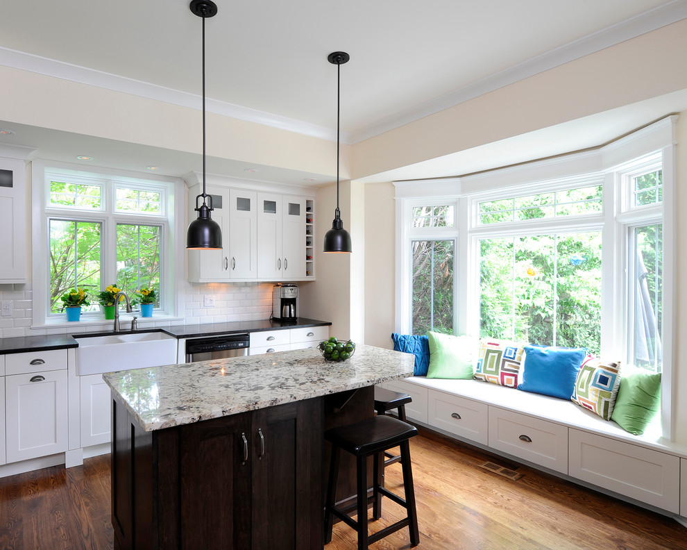 Inspiration for a timeless l-shaped kitchen remodel in Ottawa with subway tile backsplash, a farmhouse sink, granite countertops, shaker cabinets, white cabinets, white backsplash and gray countertops