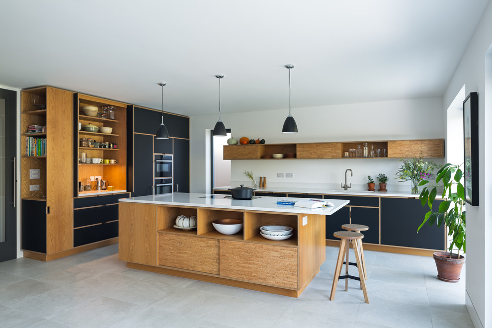 Trendy l-shaped gray floor kitchen photo in London with flat-panel cabinets, black cabinets, an island and white countertops