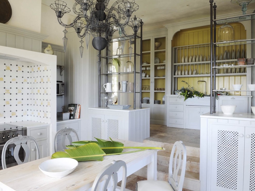 Exempel på ett mellanstort klassiskt kök och matrum, med släta luckor, grå skåp, gult stänkskydd, rostfria vitvaror och travertin golv