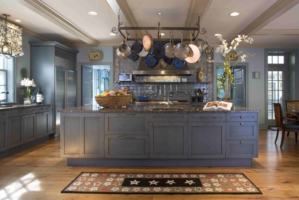 Bild på ett stort vintage kök, med en nedsänkt diskho, luckor med upphöjd panel, blå skåp, granitbänkskiva, blått stänkskydd, stänkskydd i keramik, rostfria vitvaror, mörkt trägolv och en köksö