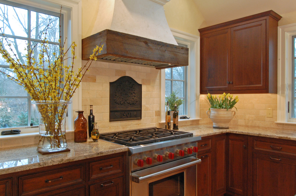 Bild på ett stort rustikt kök, med en rustik diskho, luckor med profilerade fronter, skåp i mellenmörkt trä, granitbänkskiva, beige stänkskydd, stänkskydd i stenkakel, rostfria vitvaror och en köksö