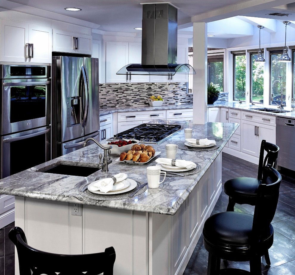 Imagen de cocina clásica de tamaño medio con armarios con paneles empotrados, encimera de granito, electrodomésticos de acero inoxidable y una isla