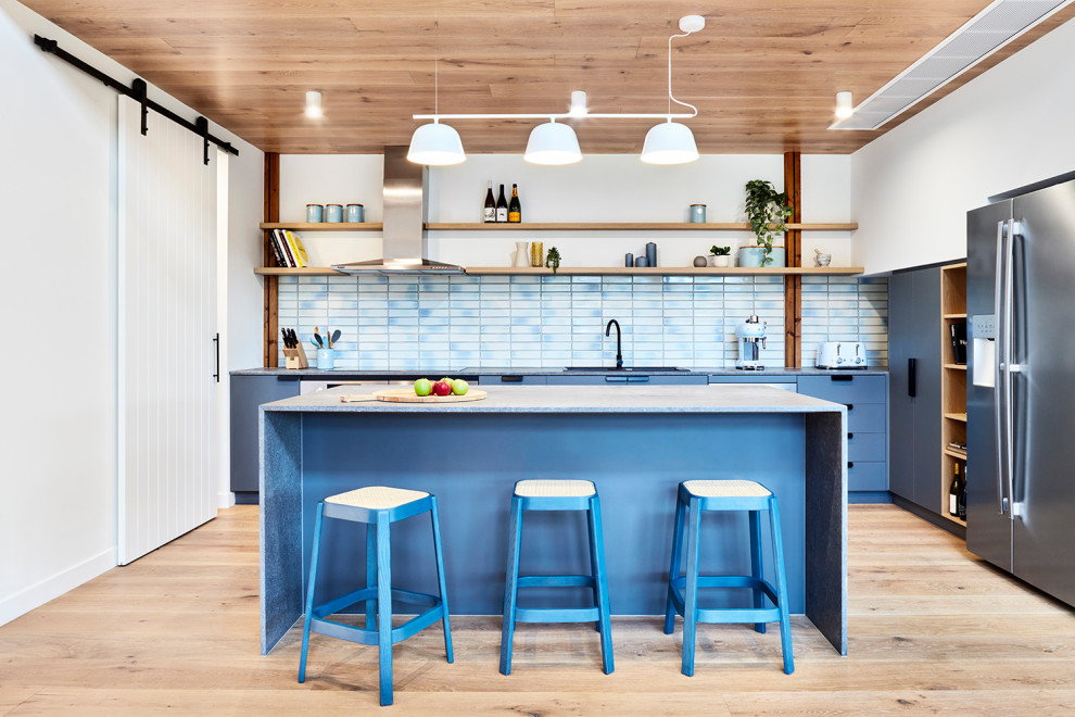メルボルンにある中くらいなコンテンポラリースタイルのおしゃれなキッチン (青いキャビネット、セラミックタイルのキッチンパネル、淡色無垢フローリング、ベージュの床、ドロップインシンク、フラットパネル扉のキャビネット、青いキッチンパネル、シルバーの調理設備、青いキッチンカウンター、板張り天井) の写真