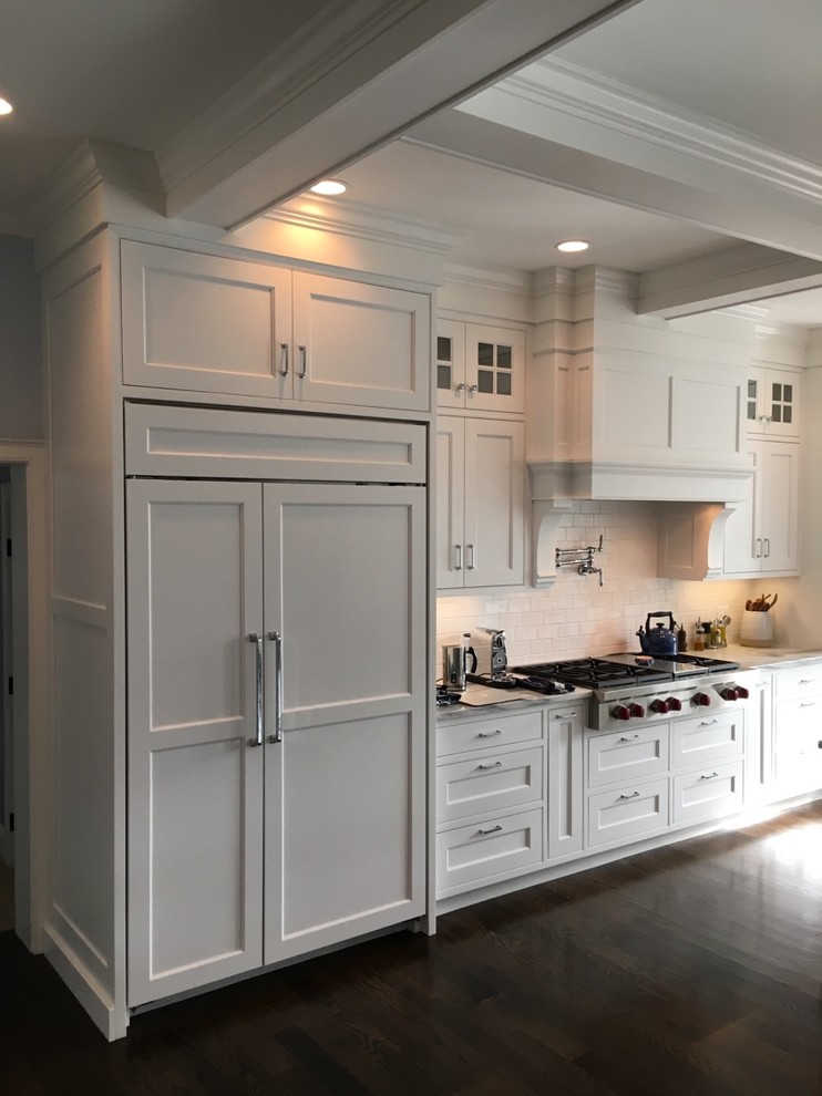 Idéer för ett stort klassiskt kök, med en rustik diskho, luckor med profilerade fronter, vita skåp, marmorbänkskiva, vitt stänkskydd, stänkskydd i tunnelbanekakel, integrerade vitvaror, mörkt trägolv och en köksö
