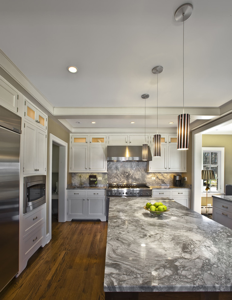 Eat-in kitchen - large traditional galley dark wood floor and brown floor eat-in kitchen idea in Chicago with an undermount sink, shaker cabinets, white cabinets, soapstone countertops, gray backsplash, stone slab backsplash, stainless steel appliances and an island