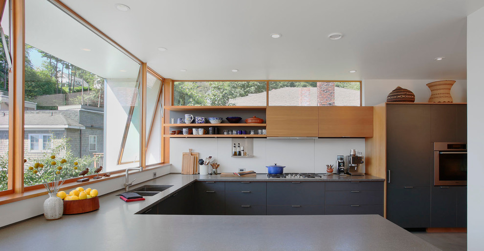 Inspiration for a mid-sized modern u-shaped concrete floor and gray floor kitchen remodel in Seattle with flat-panel cabinets, a double-bowl sink, medium tone wood cabinets, black appliances, quartz countertops, white backsplash and a peninsula