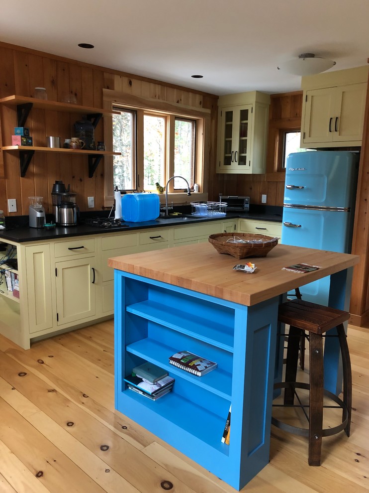 Inspiration for a craftsman light wood floor and beige floor kitchen remodel in Portland Maine with a drop-in sink, shaker cabinets, yellow cabinets, granite countertops, colored appliances, an island and black countertops