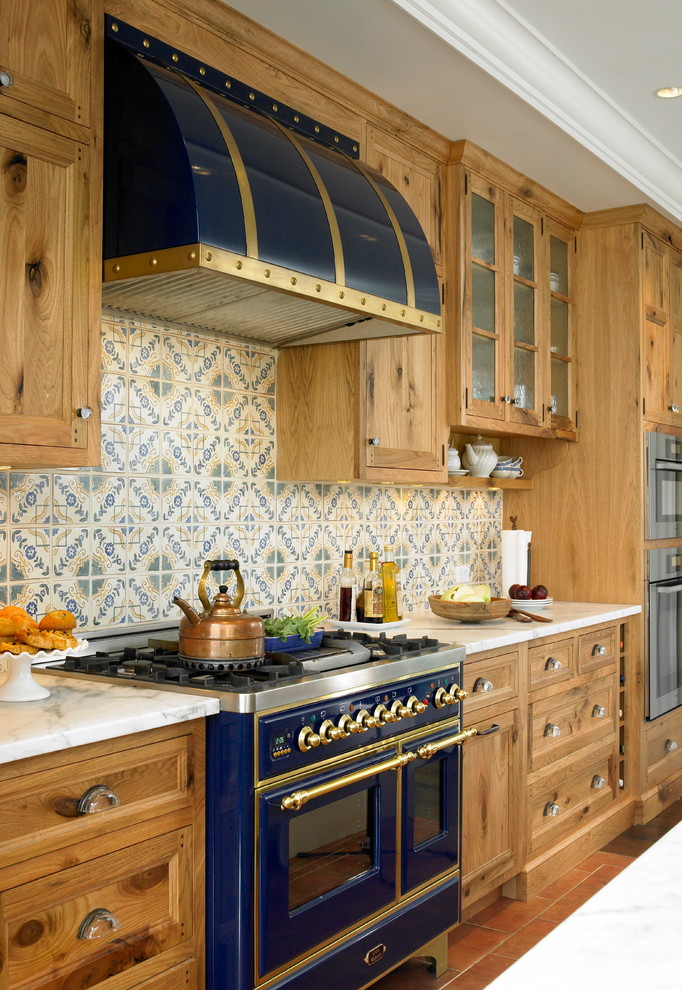 Exempel på ett stort medelhavsstil kök, med luckor med infälld panel, skåp i mellenmörkt trä, flerfärgad stänkskydd, färgglada vitvaror och klinkergolv i terrakotta