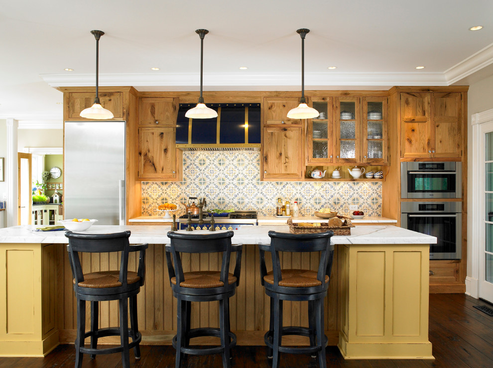 Eat-in kitchen - large traditional galley light wood floor eat-in kitchen idea in New York with a farmhouse sink, flat-panel cabinets, distressed cabinets, marble countertops, multicolored backsplash, porcelain backsplash, paneled appliances and an island