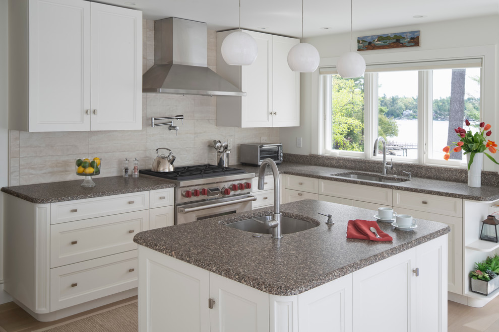 Modern inredning av ett mellanstort flerfärgad flerfärgat kök, med en undermonterad diskho, luckor med infälld panel, vita skåp, granitbänkskiva, vitt stänkskydd, stänkskydd i porslinskakel, rostfria vitvaror, ljust trägolv, en köksö och vitt golv