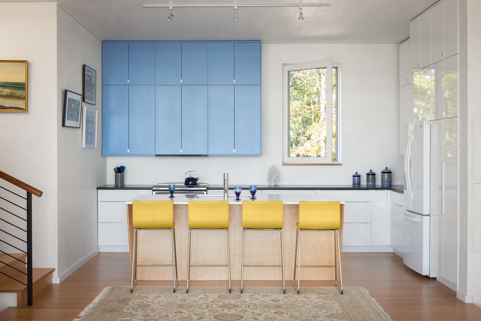 Moderne Küche in L-Form mit Kücheninsel, Unterbauwaschbecken, flächenbündigen Schrankfronten, weißen Elektrogeräten, braunem Holzboden und orangem Boden in Portland Maine