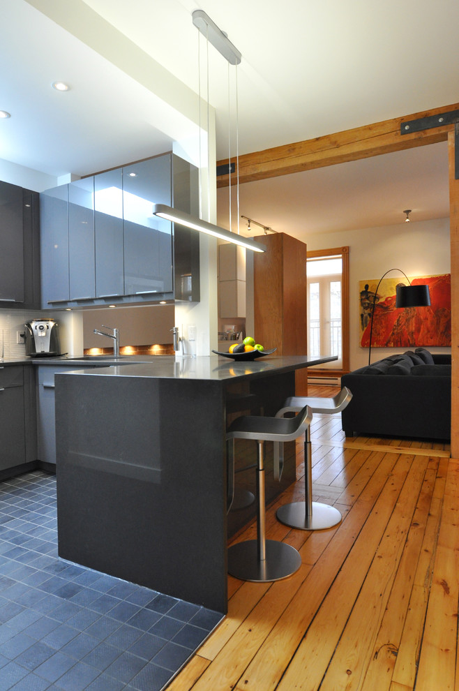 Photo of a contemporary open plan kitchen in Montreal with flat-panel cabinets, grey cabinets and white splashback.