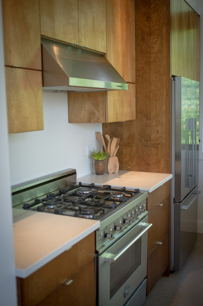Moderne Küche mit flächenbündigen Schrankfronten, hellbraunen Holzschränken, Quarzit-Arbeitsplatte und Küchengeräten aus Edelstahl in Montreal