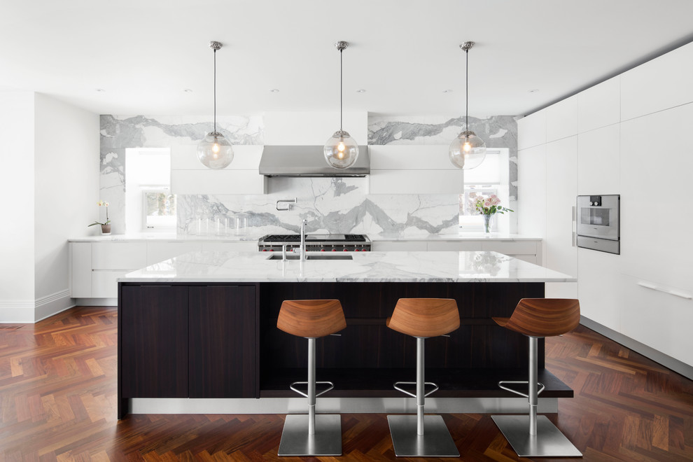 Exempel på ett stort modernt kök, med marmorbänkskiva, vitt stänkskydd, stänkskydd i marmor, rostfria vitvaror, en köksö, en undermonterad diskho, släta luckor, vita skåp, mörkt trägolv och brunt golv