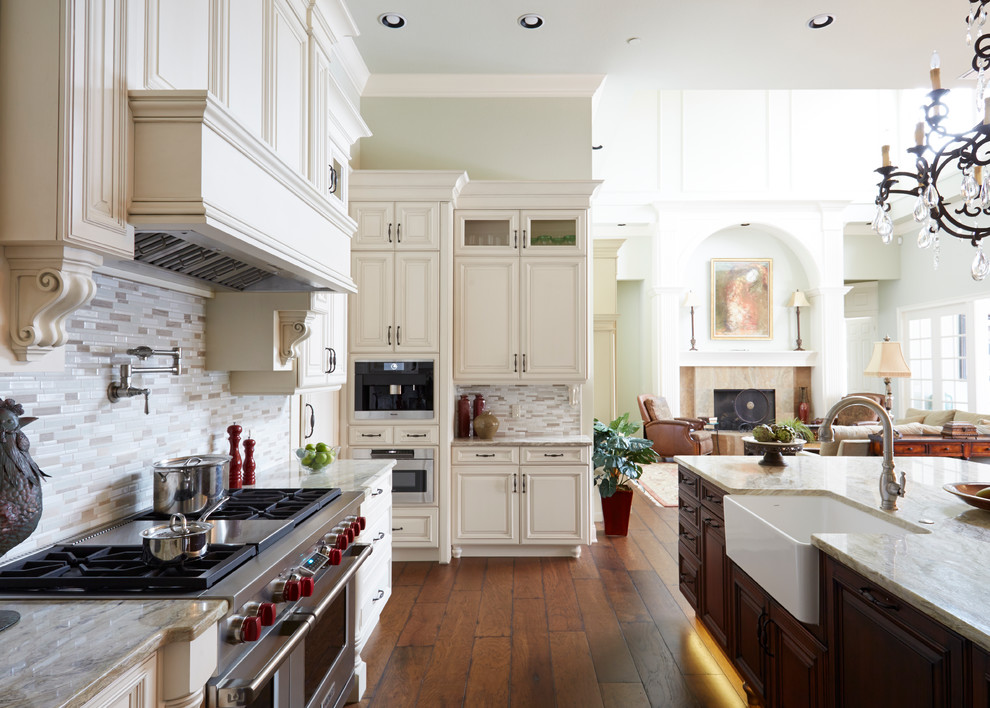 Example of a large classic u-shaped dark wood floor and brown floor eat-in kitchen design in Orlando with a farmhouse sink, raised-panel cabinets, white cabinets, quartz countertops, beige backsplash, subway tile backsplash, stainless steel appliances and an island