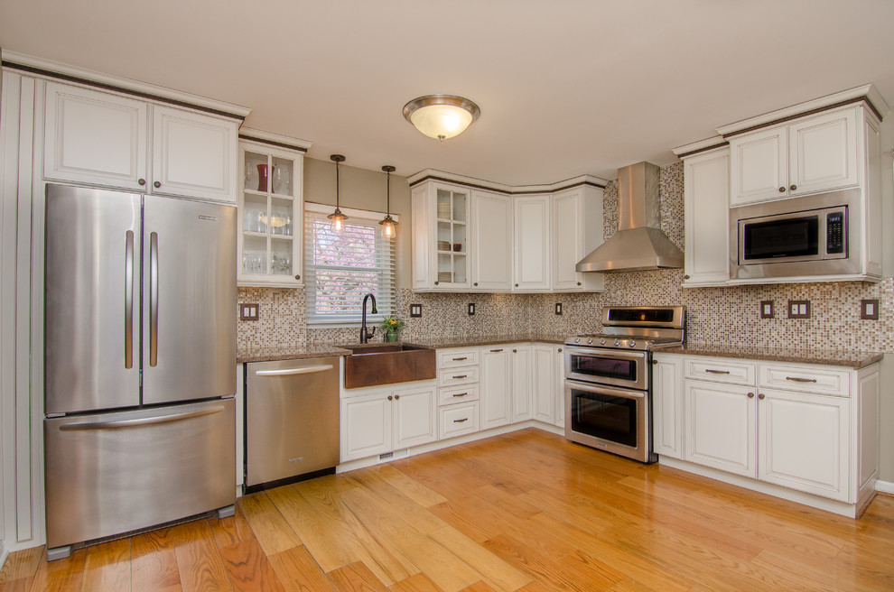 Example of a mid-sized cottage l-shaped light wood floor and beige floor eat-in kitchen design in DC Metro with a farmhouse sink, raised-panel cabinets, white cabinets, granite countertops, multicolored backsplash, stainless steel appliances, no island and mosaic tile backsplash