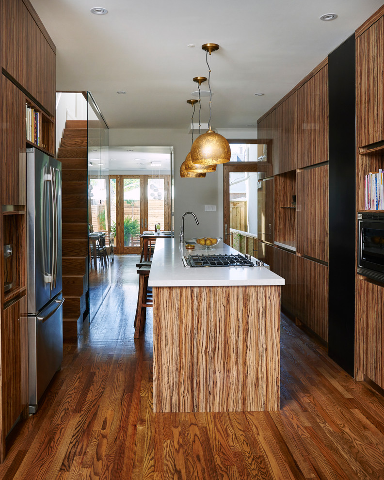 Moderne Küche mit flächenbündigen Schrankfronten, hellbraunen Holzschränken, Küchengeräten aus Edelstahl, braunem Holzboden und Kücheninsel in Toronto