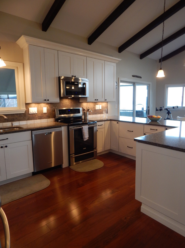 Example of a large minimalist u-shaped dark wood floor open concept kitchen design in Boston with an undermount sink, shaker cabinets, white cabinets, quartz countertops, brown backsplash, subway tile backsplash, stainless steel appliances and no island