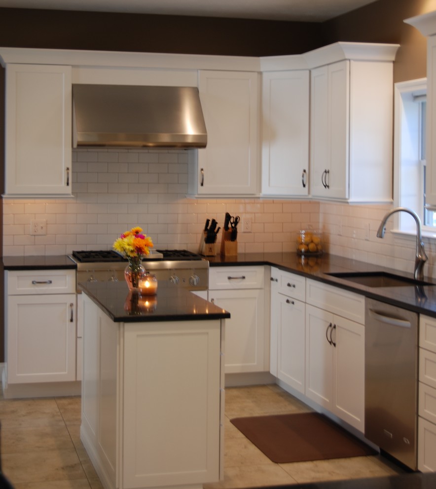 Exempel på ett mellanstort klassiskt kök, med en undermonterad diskho, luckor med infälld panel, vita skåp, bänkskiva i kvarts, vitt stänkskydd, stänkskydd i tunnelbanekakel, rostfria vitvaror, travertin golv och flera köksöar