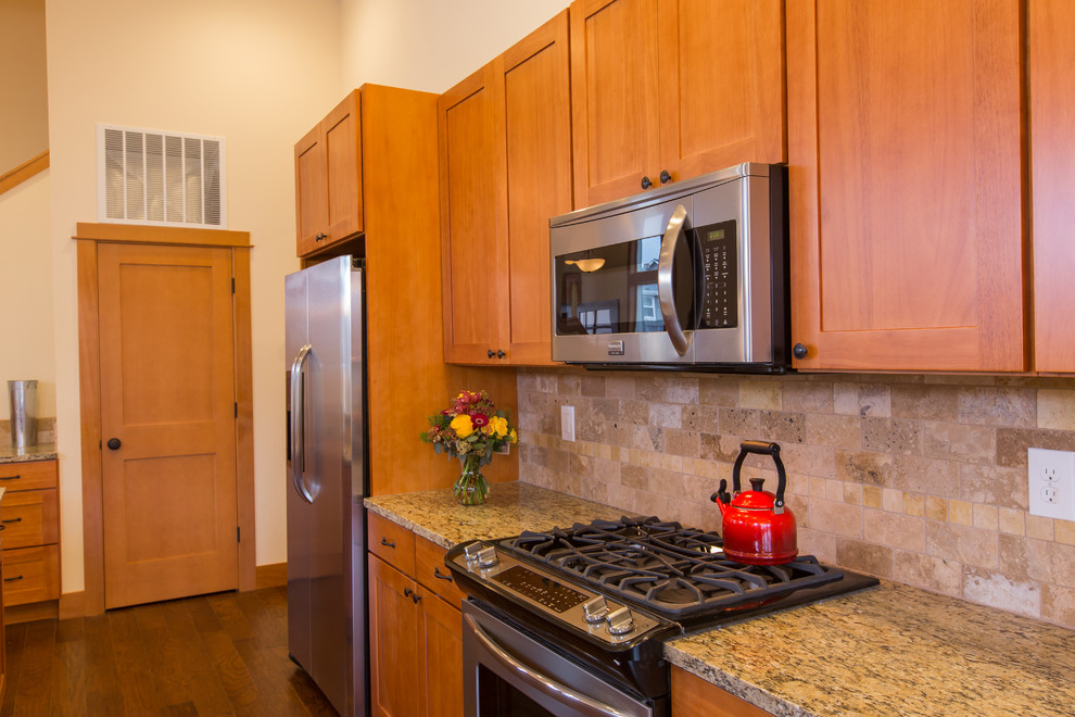 Immagine di una cucina chic con lavello a doppia vasca, ante in stile shaker, ante in legno scuro, top in granito, paraspruzzi beige e elettrodomestici in acciaio inossidabile